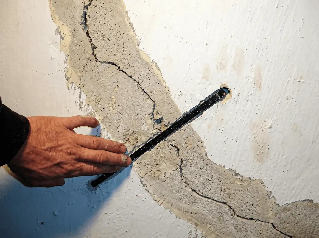 A wall with a large crack is being inspected by a professional in Rockford, IL