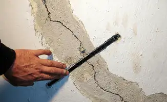 A wall with a large crack is being inspected by a professional in Rockford, IL